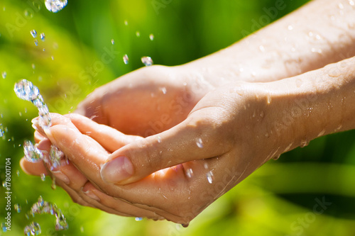 Young Woman washing hand outdoors. Natural drinking water in the palm. Young hands with water splash, selective focus