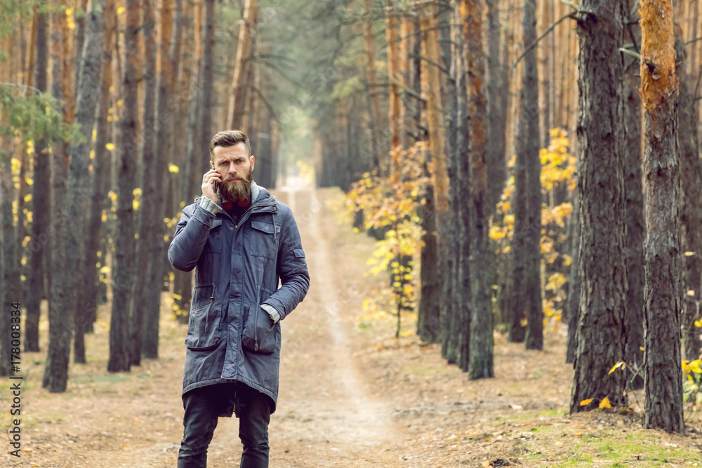 bearded frowning hipster in the forest talking on the phone bearded frowning hipster in the forest talking on the phone
