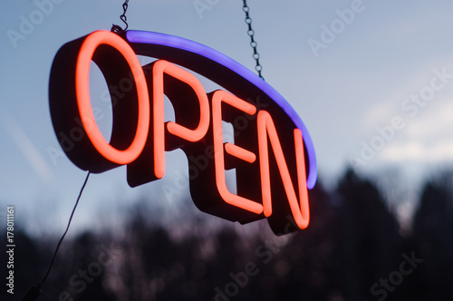 neon open sign hanging outside in the dusk photo