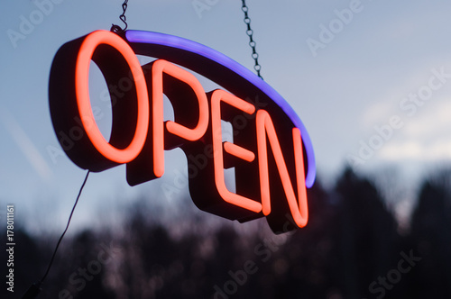 neon open sign hanging outside in the dusk