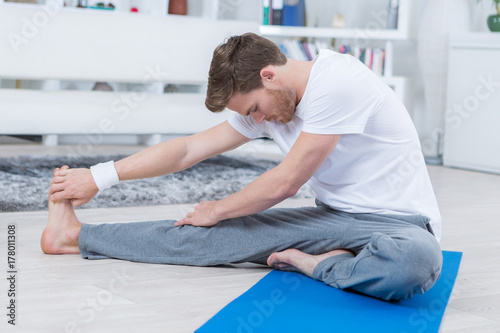 young man sitting on an exercise mat and stretching