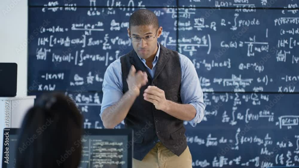 Teacher in adult education class explaining math formulas on blackboard Teacher in adult education class explaining math formulas on blackboard