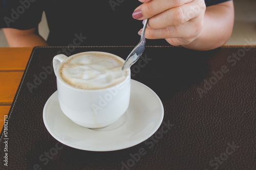 Wallpaper Mural Woman hand holding coffee spoon and stirring hot coffee in white mug on wooden table at the cafe in vintage style. Torontodigital.ca