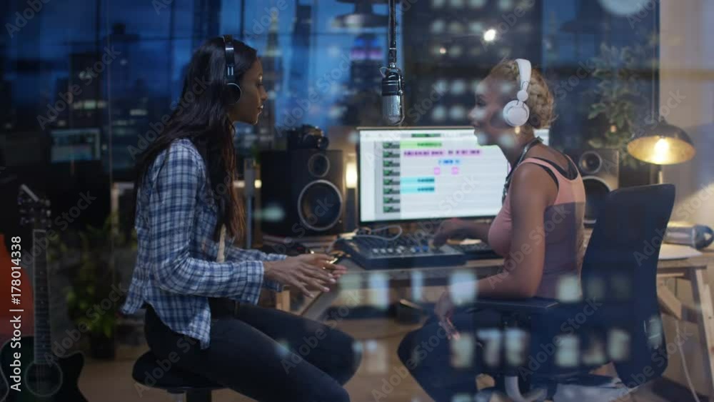 Female musicians collaborating in recording studio with view of city skyline Female musicians collaborating in recording studio with view of city skyline