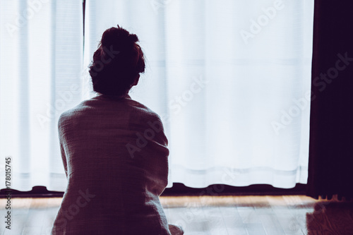 部屋の窓際に座っている寂しい女性