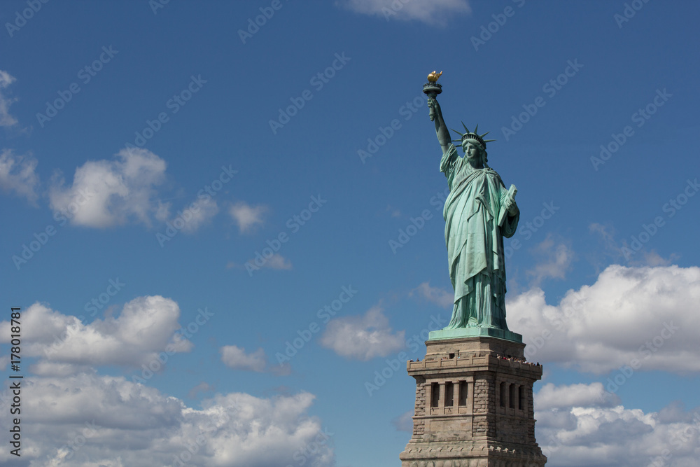 Statue of Liberty (Liberty Enlightening the World), USA freedom and democracy symbol in full size with blue sky and white clouds on background Statue of Liberty (Liberty Enlightening the World), USA freedom and democracy symbol in full size with blue sky and white clouds on background