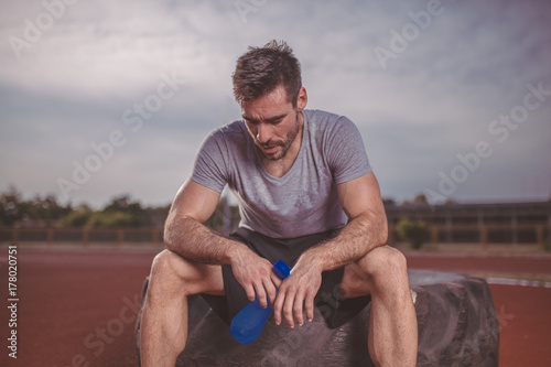 Handsome fit man resting after training and drink water.