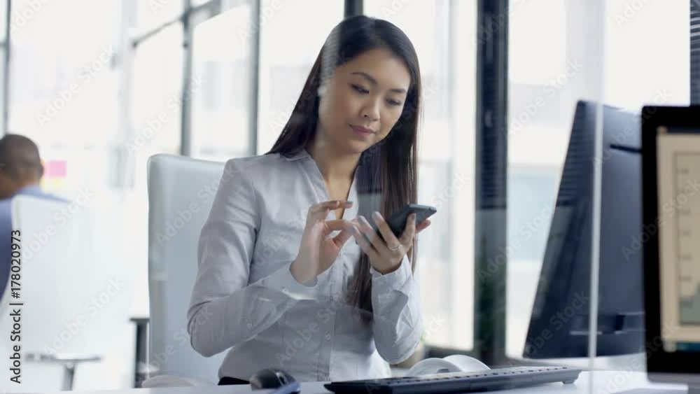  Businesswoman working on computer in office gets good news from phone call