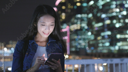 Woman sending sms on mobile phone at night