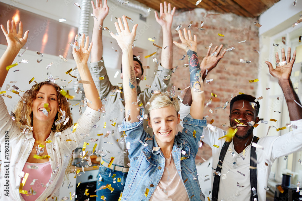 Obraz premium Joyful young people dancing at home party in confetti rain