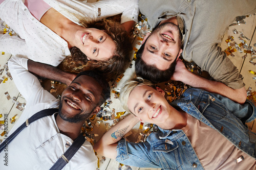 Four young companions lying on the floor with hands behind heads photo