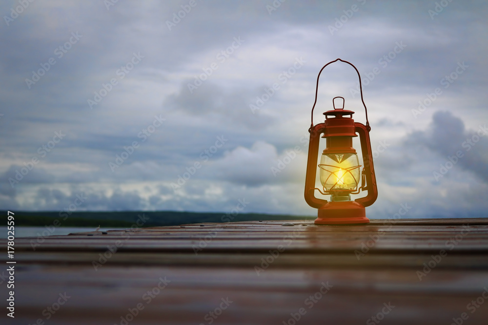 Burning lantern on a dock at a lake in the twilight Burning lantern on a dock at a lake in the twilight