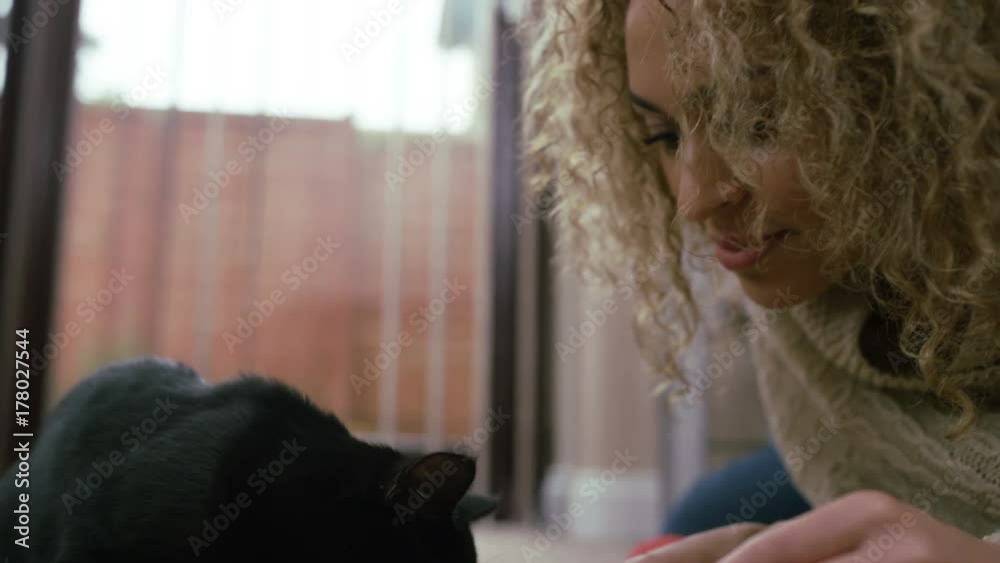 Close up of young woman playing with cute black kitten at home Close up of young woman playing with cute black kitten at home
