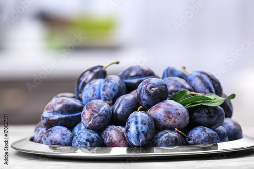 Plate with tasty ripe plums on table