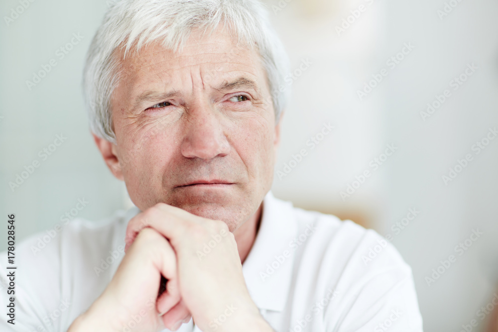 Grey-haired pensive man with his hands by chin looking aside Grey-haired pensive man with his hands by chin looking aside