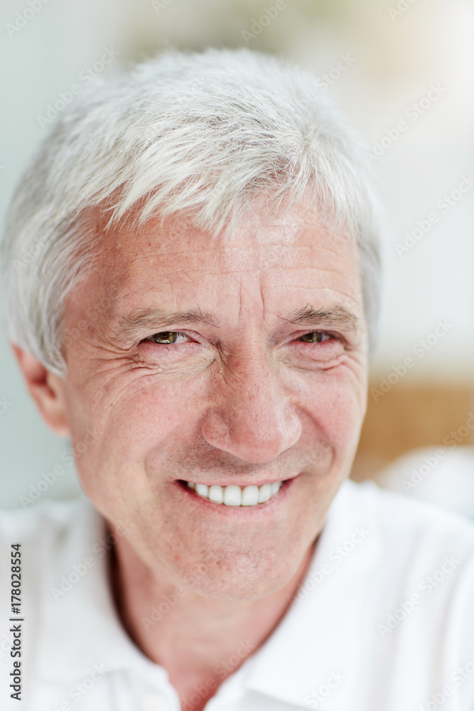 Senior grey-haired man with toothy smile looking at camera Senior grey-haired man with toothy smile looking at camera