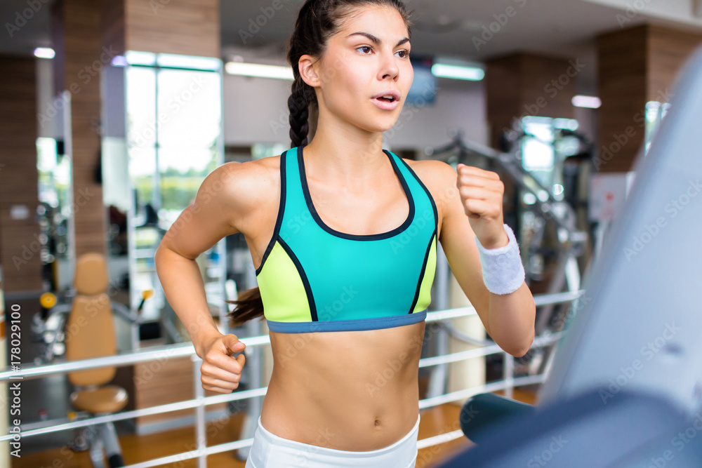 Modern girl running on treadmill during workout in gym Modern girl running on treadmill during workout in gym