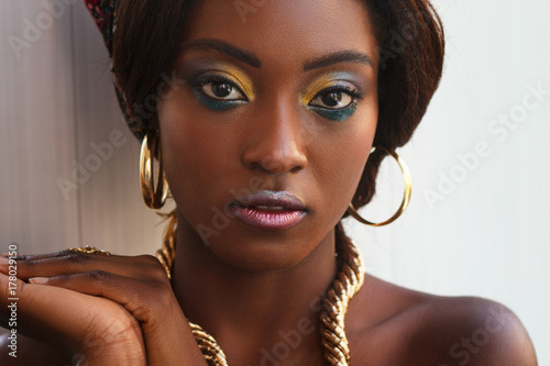 Beautiful dark skin afro girl with professional make-up and gold jewelry