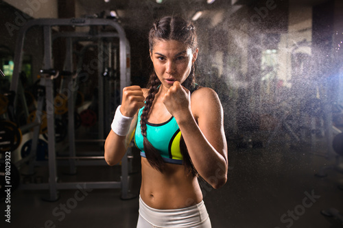 Brave sporty girl showing her fists during workout in gym
