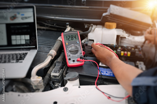 Close up of auto mechanic jumping battery car,check voltage level car battery,helping concept.