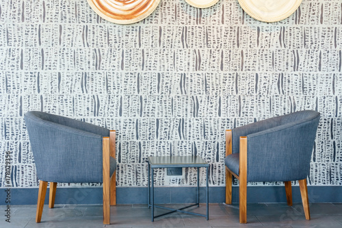 Modern black chairs are standing near square wooden tables in a coffee shop or a restaurant with a black floor and white walls.