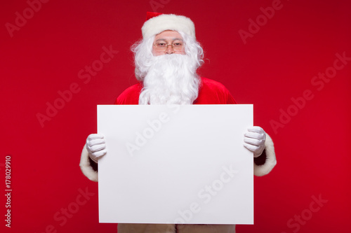 Santa Claus pointing in blank advertisement banner isolated on red background with copy space