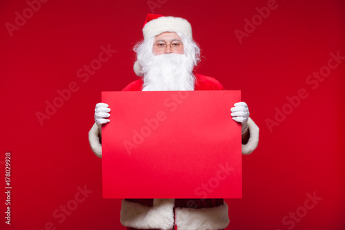 Santa Claus pointing in blank advertisement banner isolated on red background with copy space red leaf © satyrenko