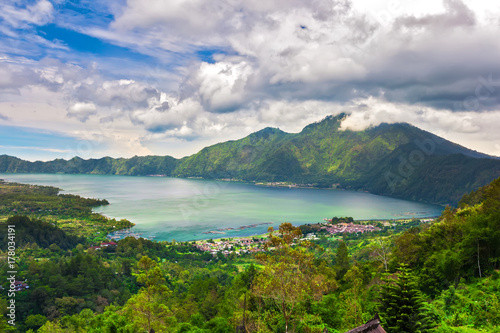 Panoramic view of a lake surrounded by mountain, tropical landscape with colorful clouds in the sky. Fisheries and settlements on the shore. Danau Batur, Gunung Batur, Kintamani, Bali, Indonesia. photo