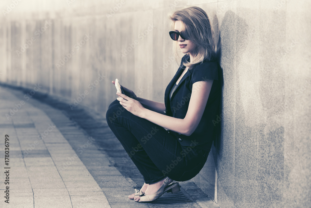 Young fashion woman with tablet computer sitting at the wall Young fashion woman with tablet computer sitting at the wall
