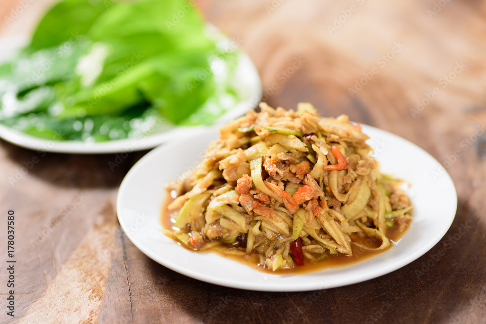 Thai food,spicy mango salad on white dish with vegetable