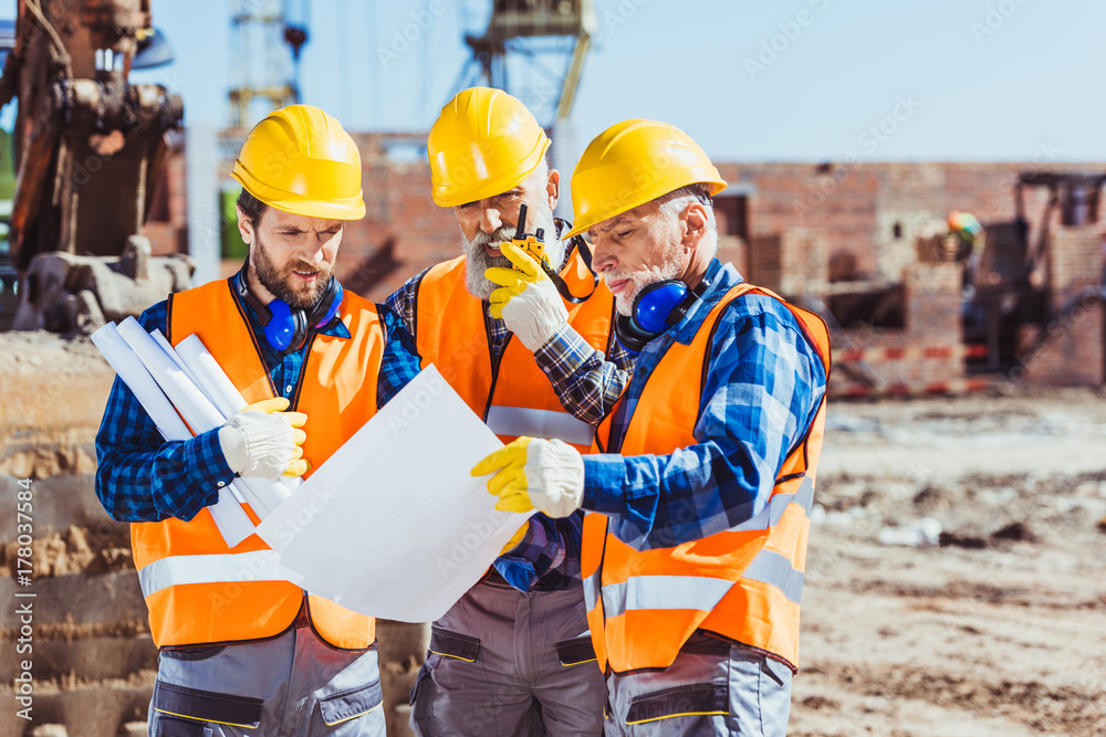 Workers examining building plans Workers examining building plans