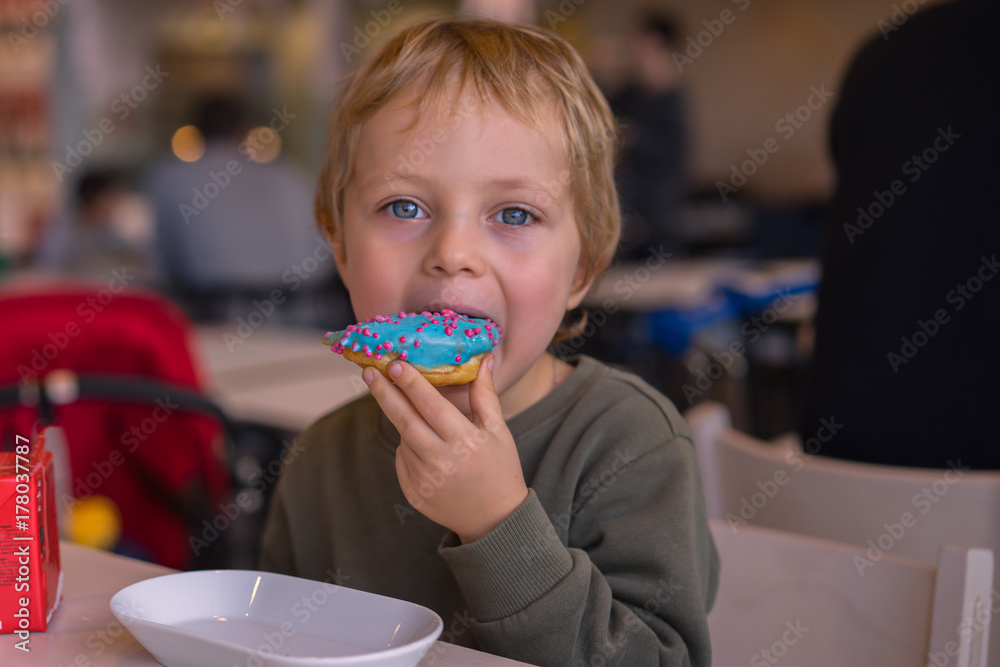 Cute baby boy eating sweet donut in cafe Cute baby boy eating sweet donut in cafe