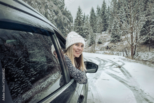 Woman at winter time. Yoyng female looking in window of her blac