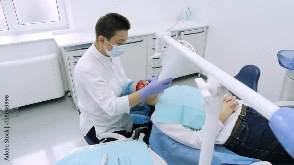 Woman getting UV whitening at the dentist's office by an ultra violet machine. Woman getting UV whitening at the dentist's office by an ultra violet machine.