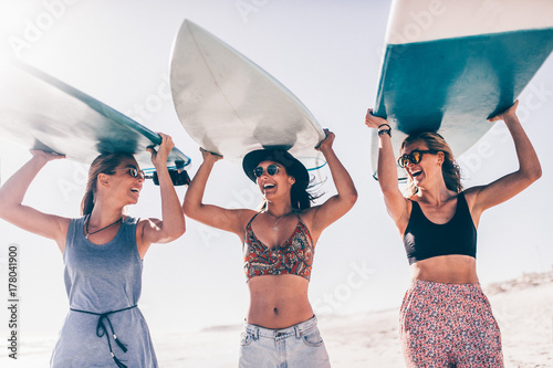 Happy young adult friends having fun at the beach surfing photo
