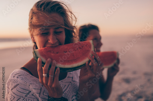 Woman eating watermelon at the beach in sunset photo