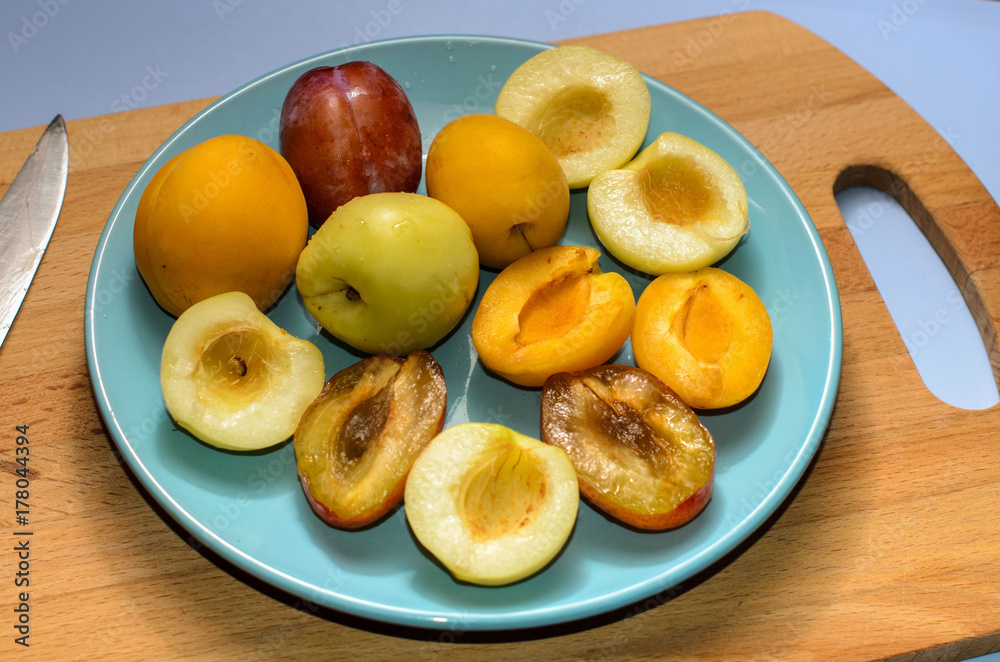 Summer fruits: apples, pears, apricots, plums on a blue plate