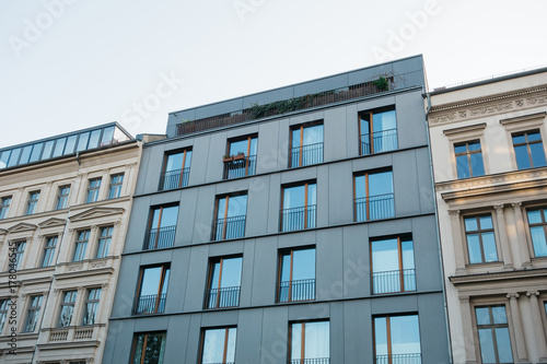 futuristic facade next to historical apartment houses