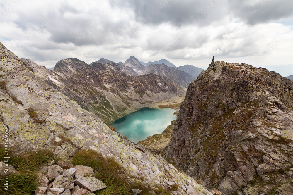 Hiking woman standing on high peak and pointing on rocky Tatra mountains Hiking woman standing on high peak and pointing on rocky Tatra mountains