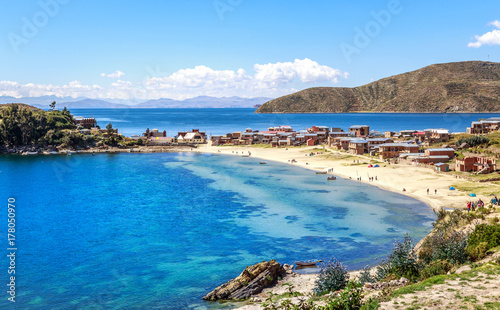 Blue water and coast of Titicaca lake, boats, walking people and bolivian village at Incas Island of the Sun, Bolivia, south America