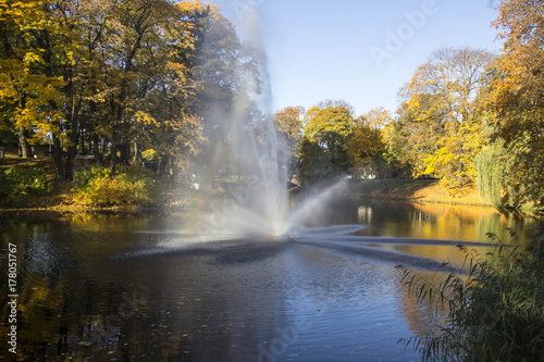 Fountain and rainbow in Riga Canal that flows through Bastion park autumn background with colored leaves  Bastejkalns . Latvia autumn 