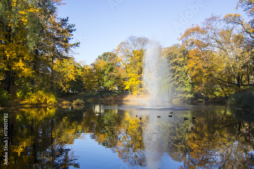 Fountain and rainbow in Riga Canal that flows through Bastion park autumn background with colored leaves (Bastejkalns). Latvia autumn © Uldis