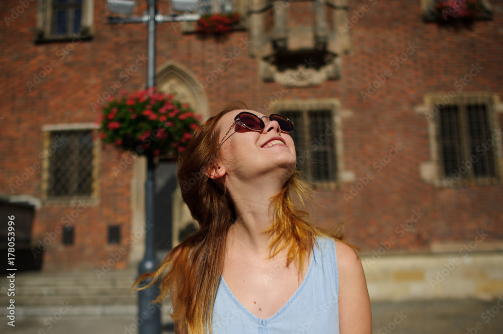 Charming girl in sunglasses against the backdrop of a beautiful old building.