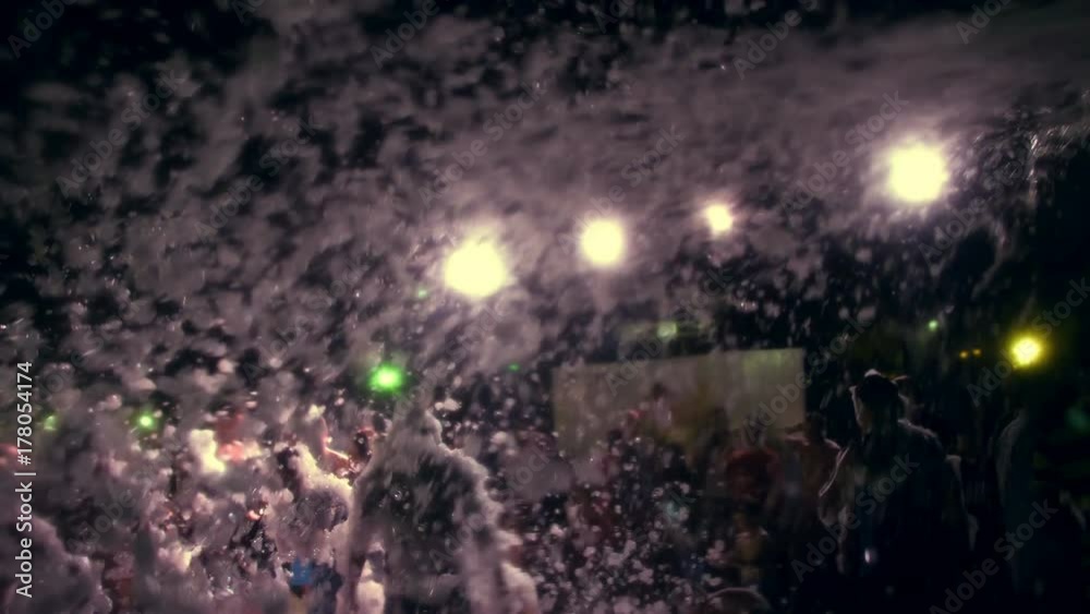 summer, night, foam party, in the rays of soffits, foam poured into the dancing people