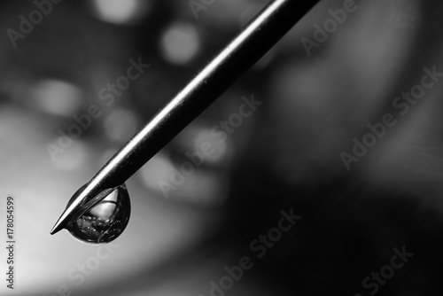 Black and white photo of a drop on the tip of a needle macro