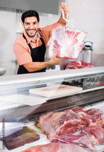 Man butcher is demonstraiting meat in the market.
