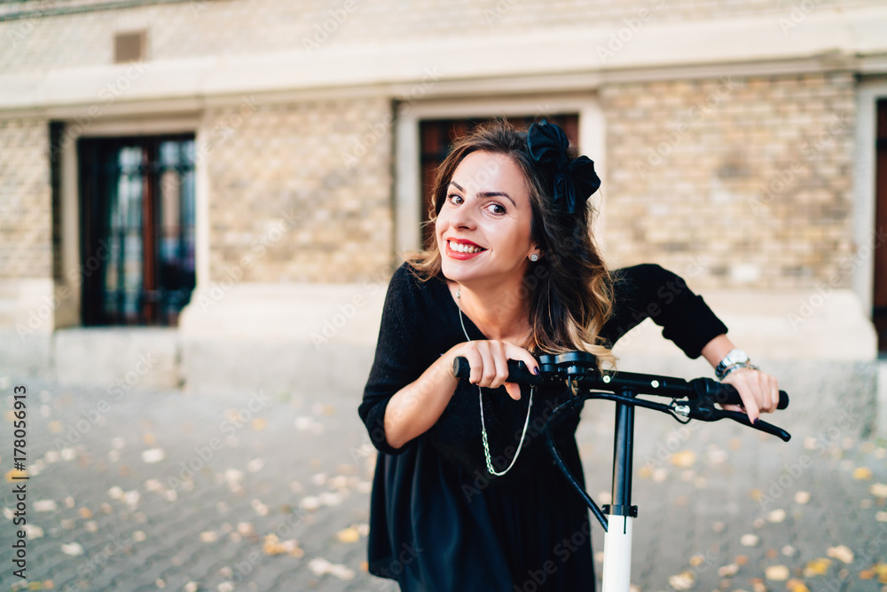 portrait of beautiful girl smiling and riding electric scooter. Autumn details in modern city, urban landscape portrait of beautiful girl smiling and riding electric scooter. Autumn details in modern city, urban landscape