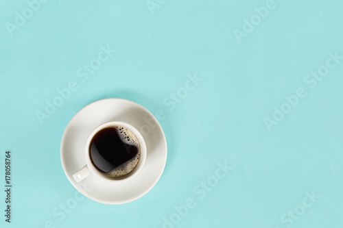 A cup of black coffee on blue background. View from above.