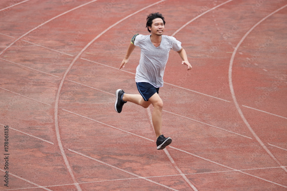 Young athlete Asian man running on racetrack in stadium. Healthy active lifestyle concept.