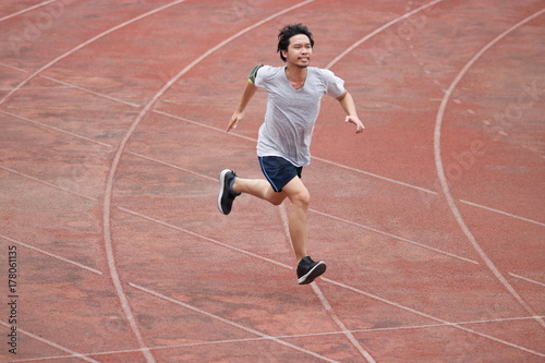 Young athlete Asian man running on racetrack in stadium. Healthy active lifestyle concept. © tuaindeed